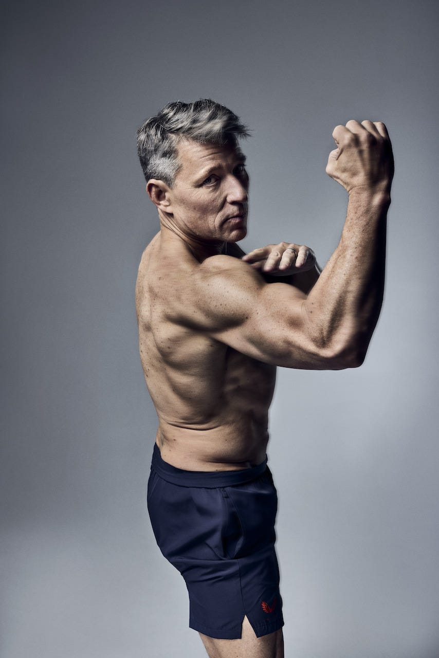a muscular man flexing his arm while wearing shorts a muscular man flexing his arm while wearing shorts