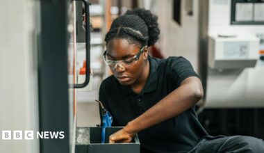 Concentrated young female worker examining mechanics while working in factory.