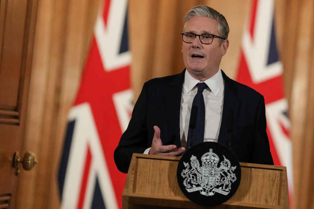 Britain's Prime Minister Keir Starmer at a press conference in Downing Street, speaking at a podium with the royal coat of arms.