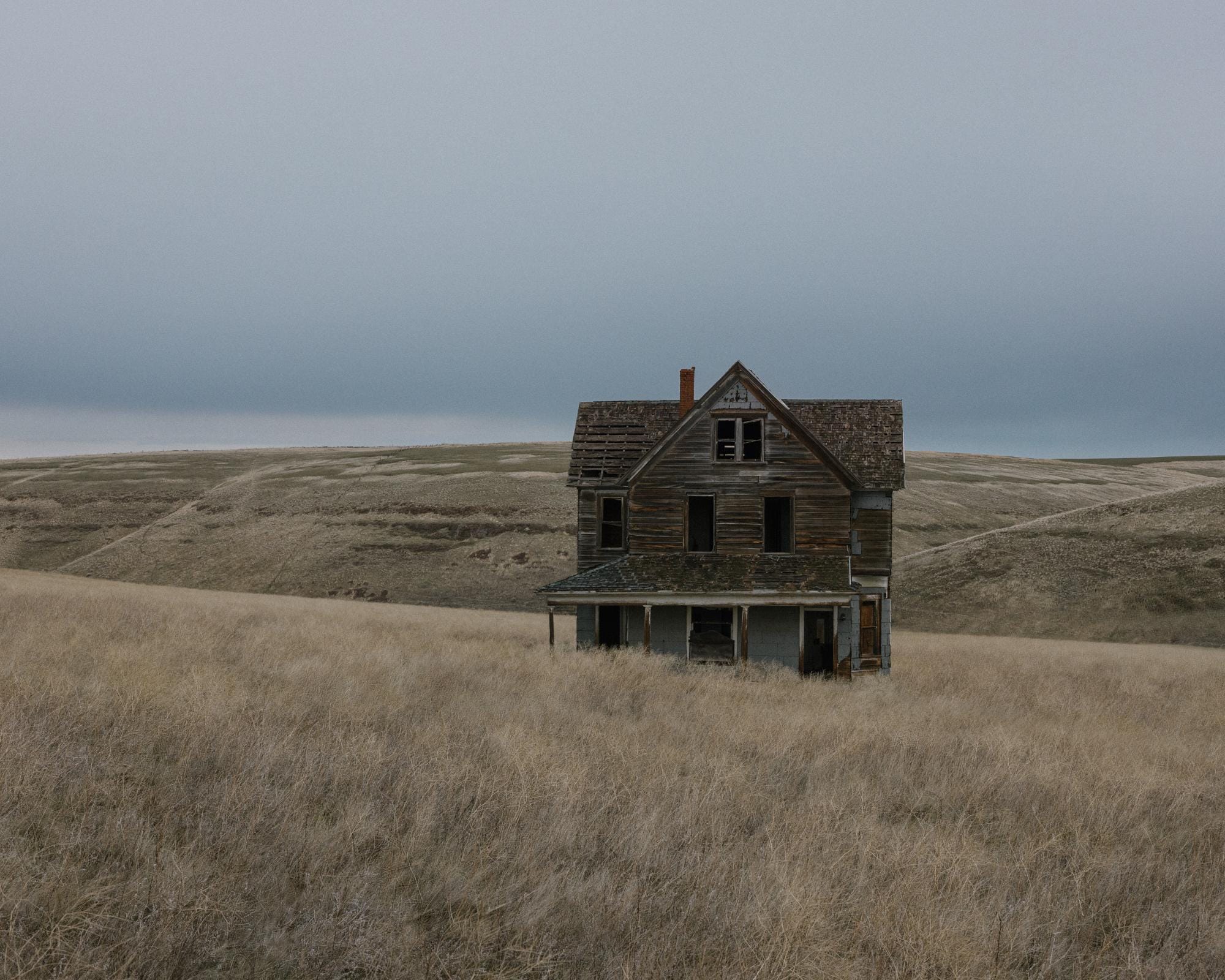 a photograph by Brendon Burton of a derelict house standing alone in plains