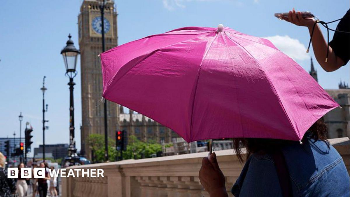 A person shielding from the Sun under an umbrella with the Houses of Parliament in the background