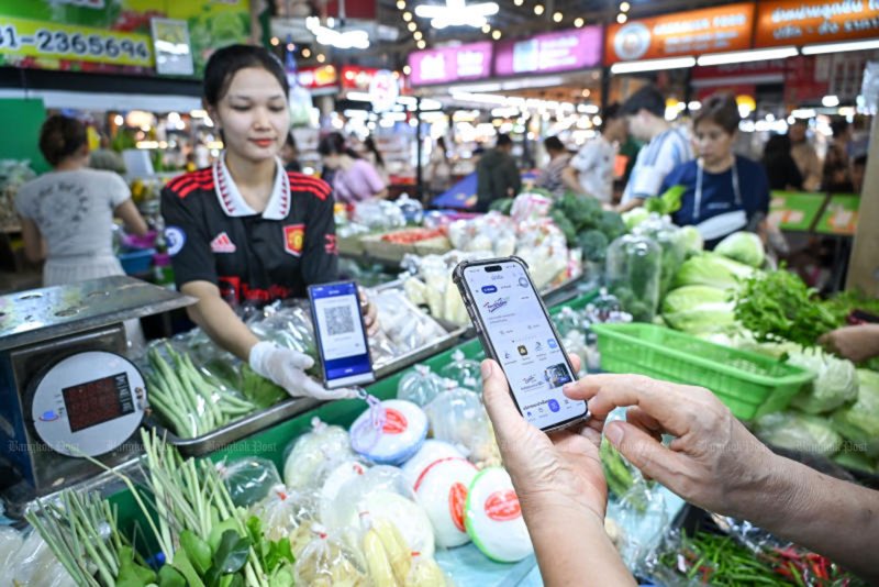 A customer scans a QR code to pay for vegetables at a stall participating in the government’s Thai Chuay Thai Plus co-payment scheme at a fresh market in Thon Buri, Bangkok on June 1. (Photo: Chanat Katanyu)