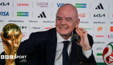FIFA president Gianni Infantino, in dark suit and tie and white shirt, speaks next to the World Cup trophy and a football during a news conference on the eve of the opening match of the 2026 World Cup
