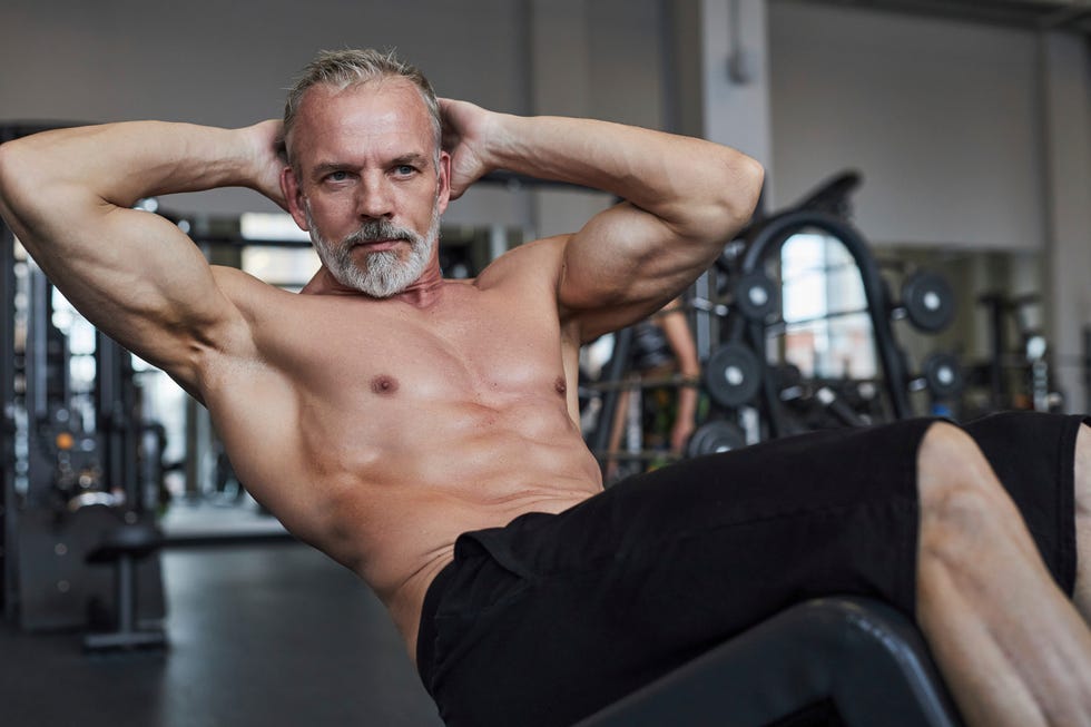 Shirtless mature man doing curl up exercise in gym shirtless mature man doing curl up exercise in gym
