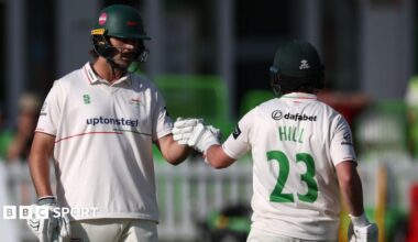 Lewis Hill with HILL 23 in green letters on the back of his white shirt punches gloves with Ben Green (left)