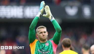 Goalkeeper Daniel Peretz wearing a green goalkeeping shirt, applauds the fans at the end of a game while playing for Southampton.