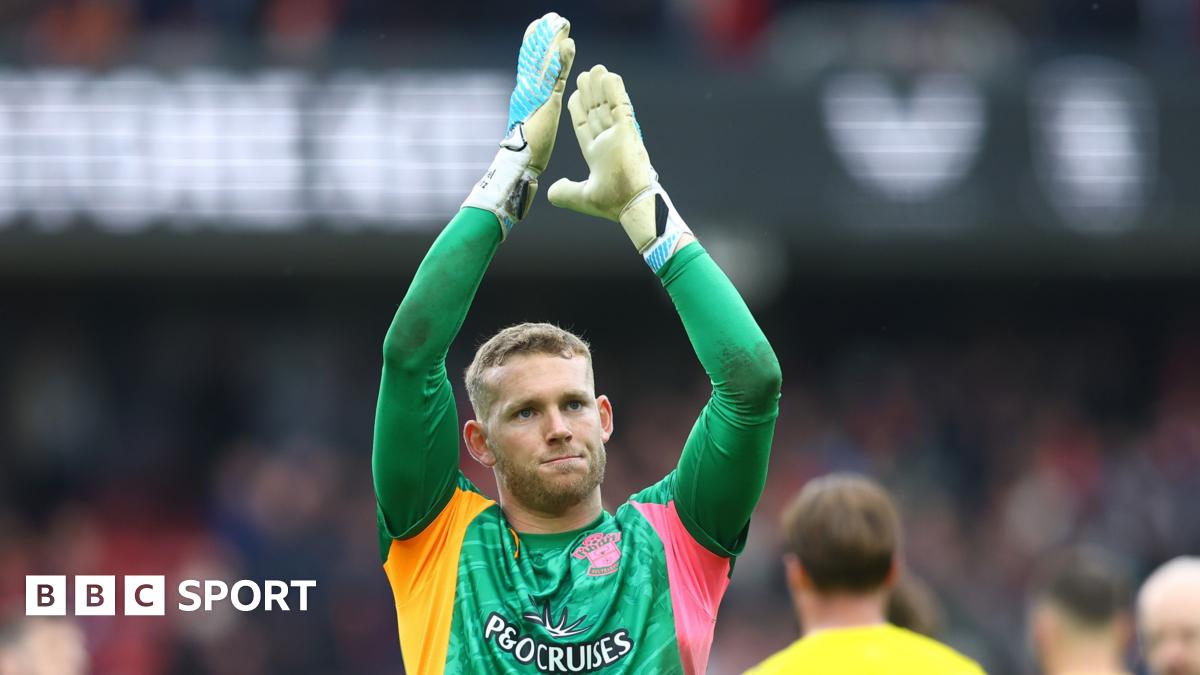 Goalkeeper Daniel Peretz wearing a green goalkeeping shirt, applauds the fans at the end of a game while playing for Southampton.