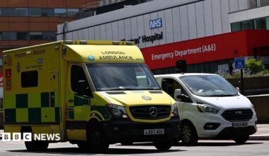 Yellow London Ambulance Service ambulance parked outside an NHS hospital emergency department (A&E).
