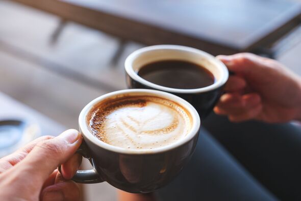 Closeup image of a man and a woman clinking white coffee mugs in cafe Closeup image of a man and a woman clinking white coffee mugs in cafe
