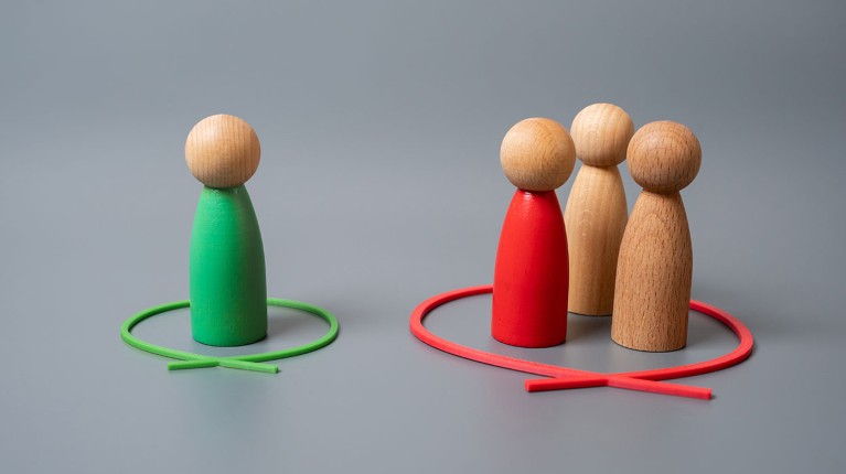 Four wooden pawns are grouped by coloured circles to leave a single one isolated and outnumbered.