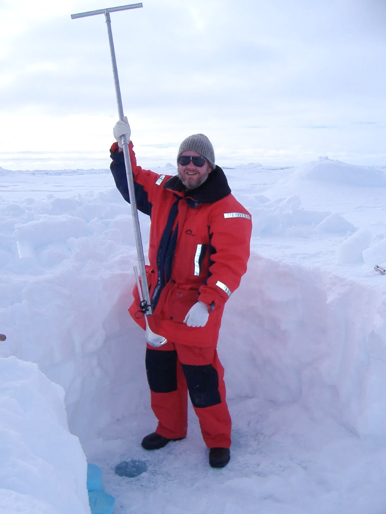 David Thomas holds up a pole with a metal ladle tied to the end while stood on an ice floe in the Weddell Sea in the Antarctic.