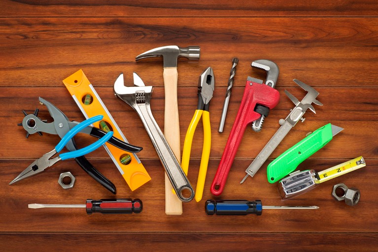 A selection of different colourful tools arranged neatly on a wood background.