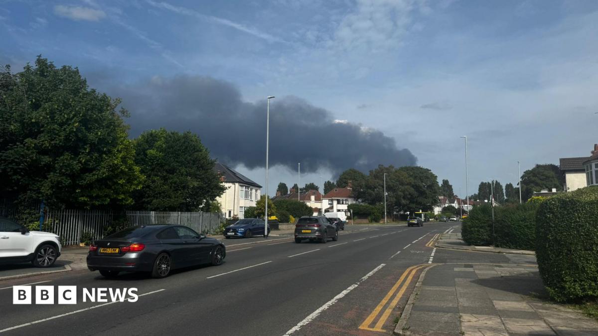 A large plume of smoke can be seen from a pavement at the side of a road in Liverpool.