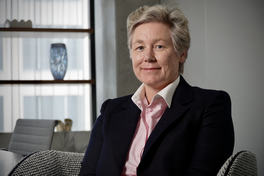 A woman sits in an office with a smile on her face.