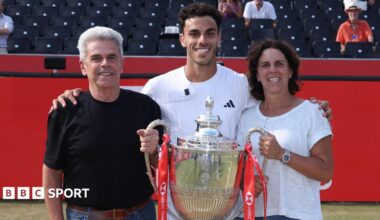Francisco Cerundolo poses with the Queen's trophy alongside his parents