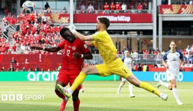 Bosnia goalkeeper Nikola Vasilj collides with Canada striker Tani Oluwaseyi.