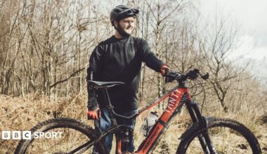 Tom Wheeler sits at a picnic table with his mountain bike behind him.