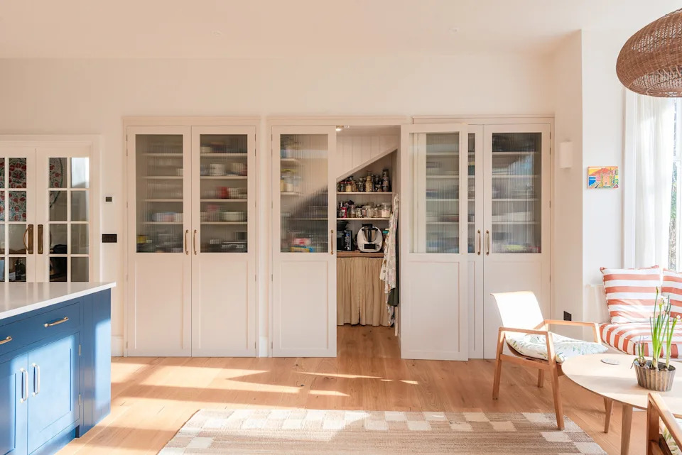 A walk-in pantry and breakfast station sit neatly behind a wall of cabinetry