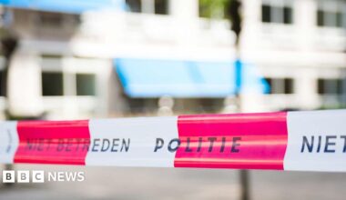A stock image of white-and-red striped Dutch police tape, which reads 'Politie'.