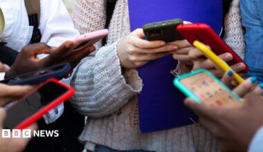 A close up of a group of people using mobile phones - their hands and the phones are visible.