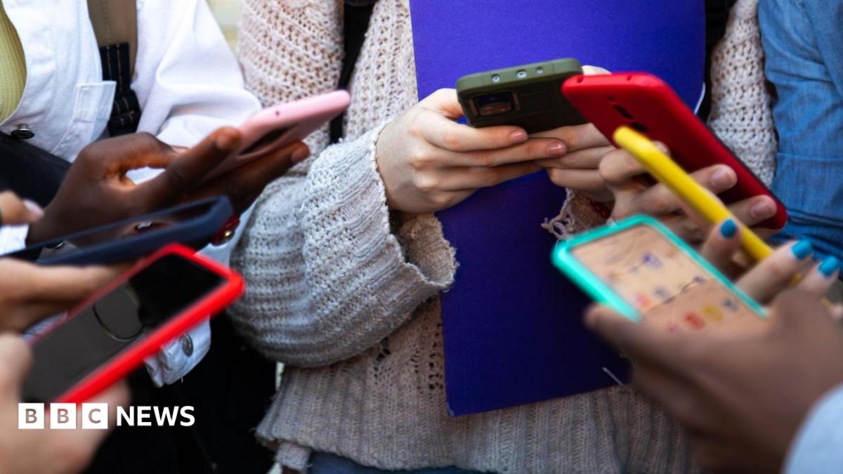 A close up of a group of people using mobile phones - their hands and the phones are visible.