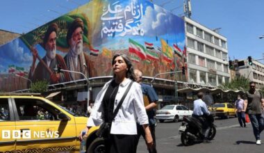 Iranians walk past a billboard of the late Iranian supreme leaders, 15 June