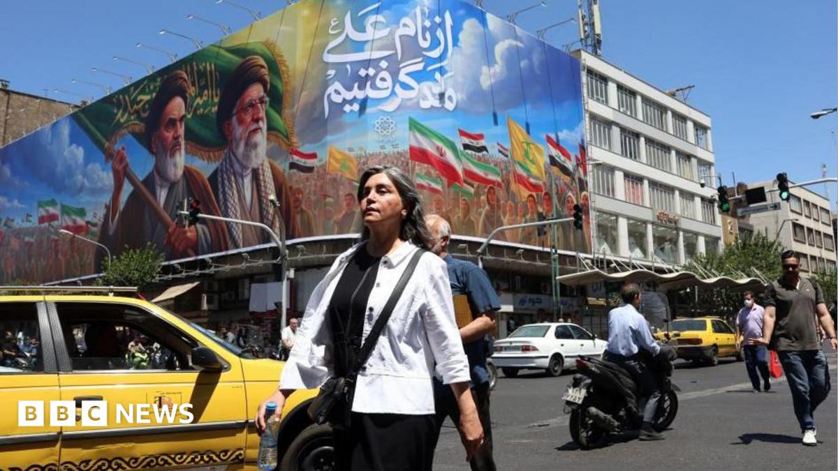 Iranians walk past a billboard of the late Iranian supreme leaders, 15 June