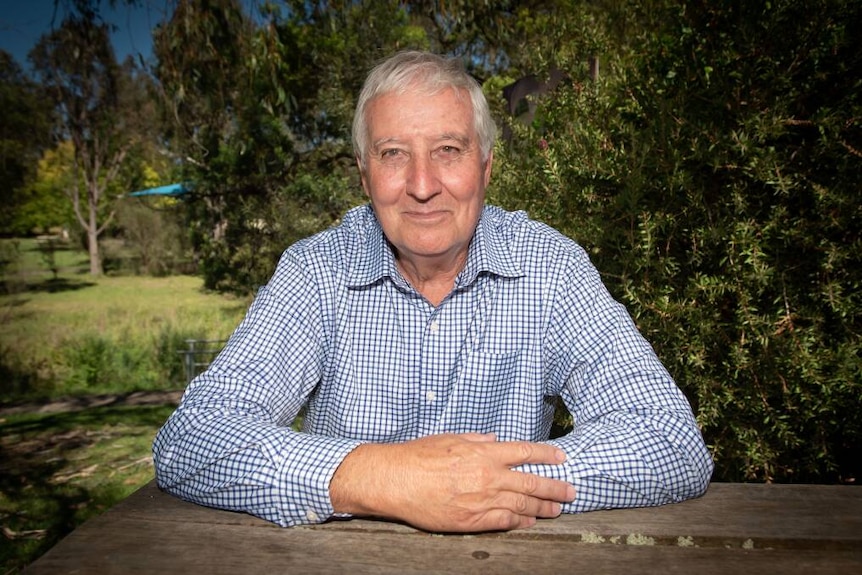 A man sitting at a park bench with his arms folded