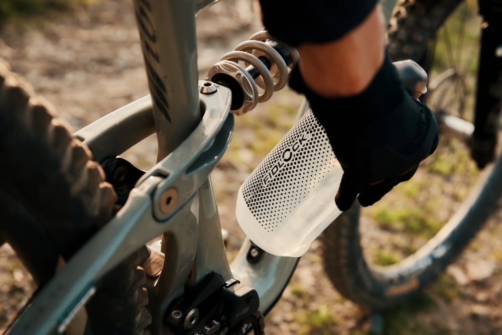 The Fidlock Twist system is demonstrated being used in the tight inside dimension of a full-suspension mountain bike where a tradition drop in bottle cage system may not permit easy access to hydration on the move.