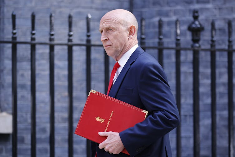 John Healey after resigning carrying his red minister's folder