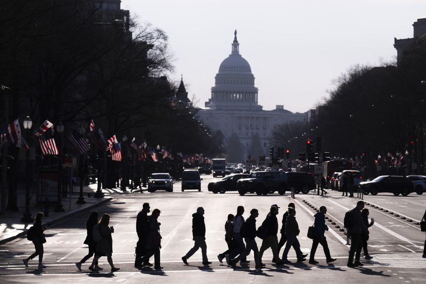 Commuters cross Pennsylvania Avenue in downtown Washington, DC, on March 20, 2025.