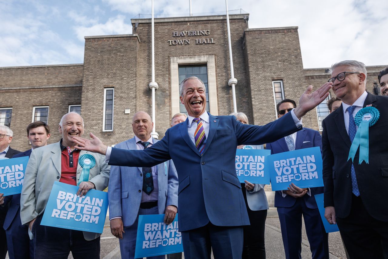 Reform UK leader Nigel Farage, center, poses with winning councillors outside Havering Town Hall in Romford, England, following the 2026 local election results on May 8.