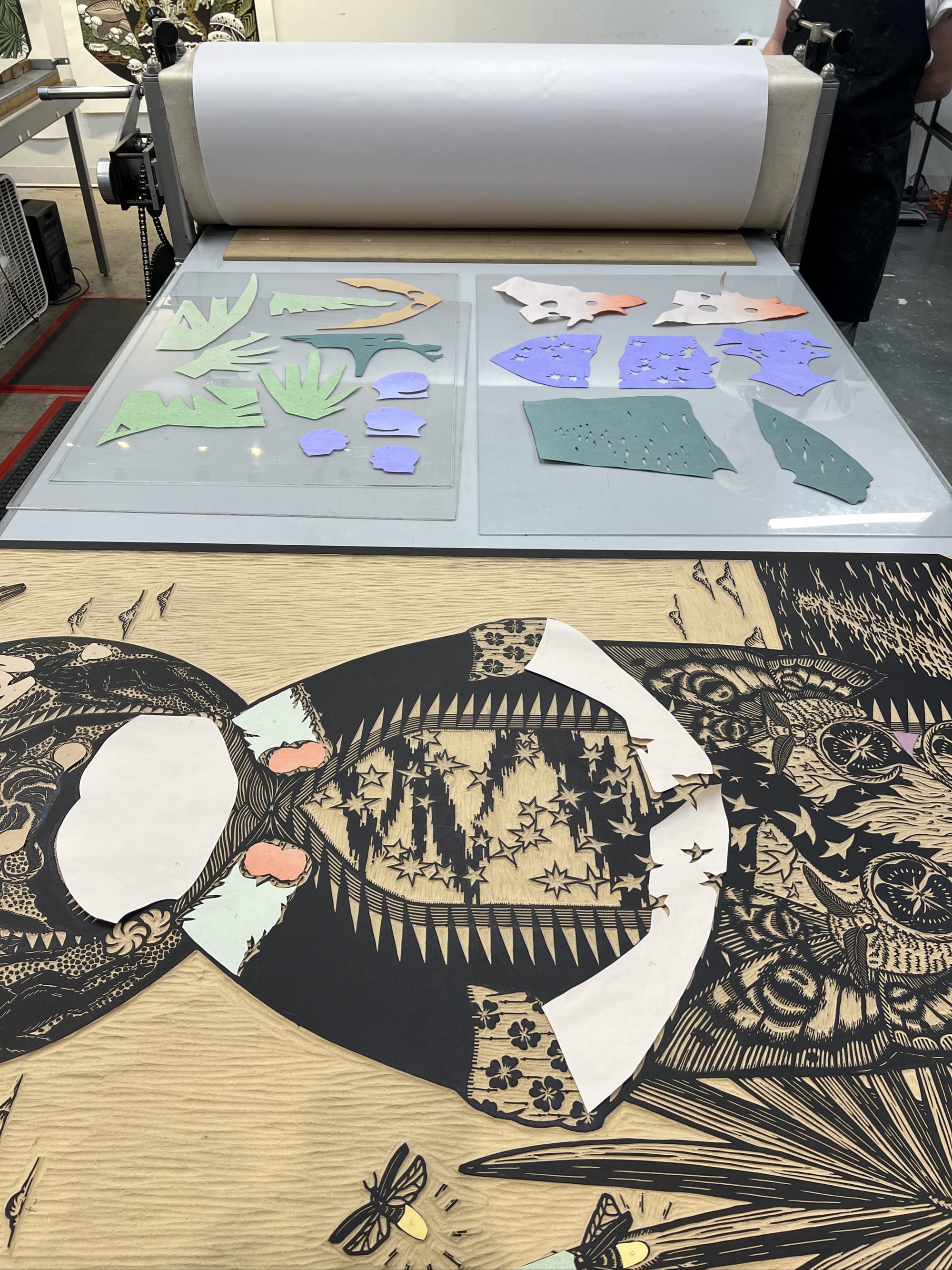 paper being collaged onto a large carved woodblock