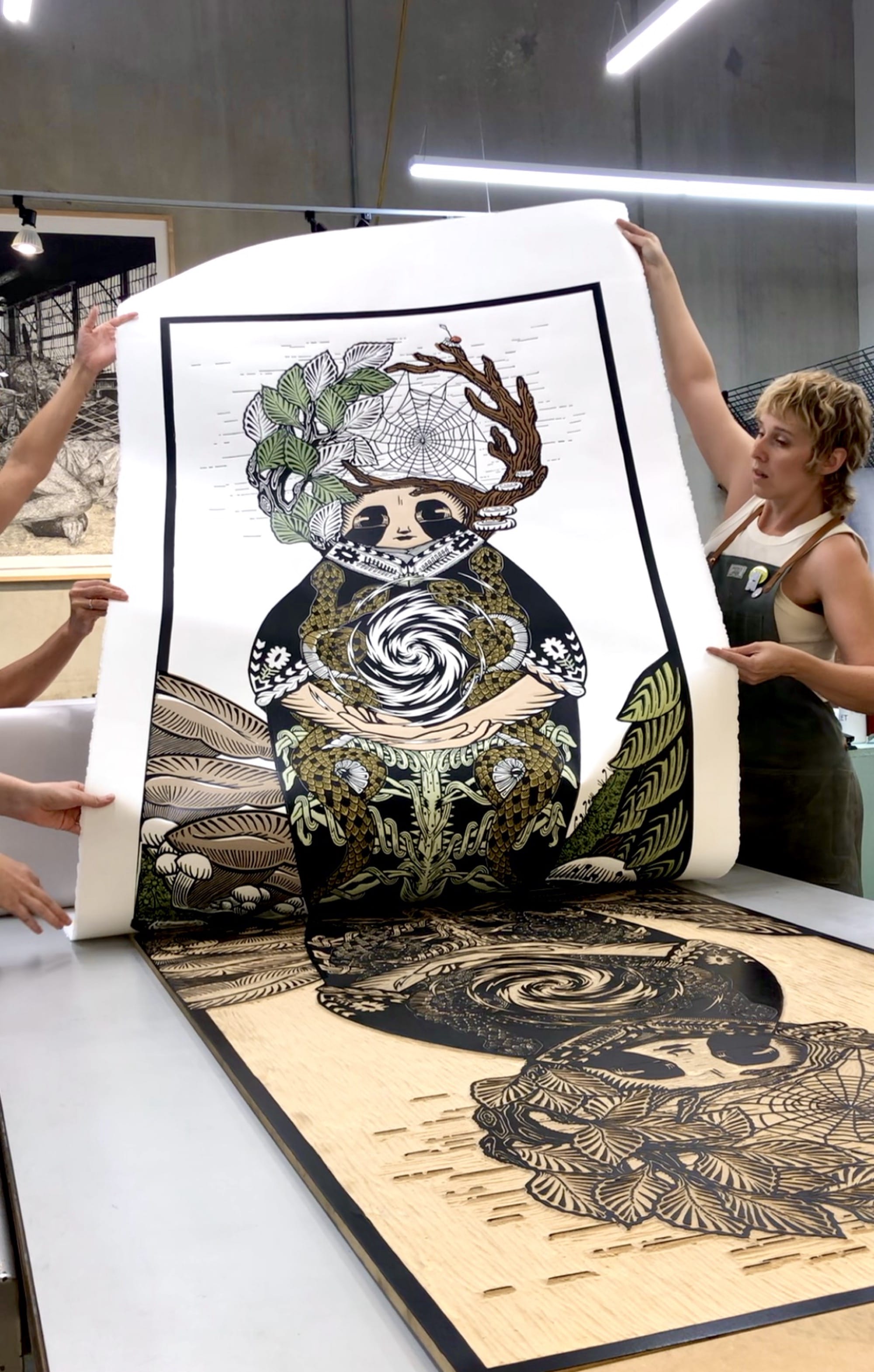 a large woodblock print being pulled by two artists