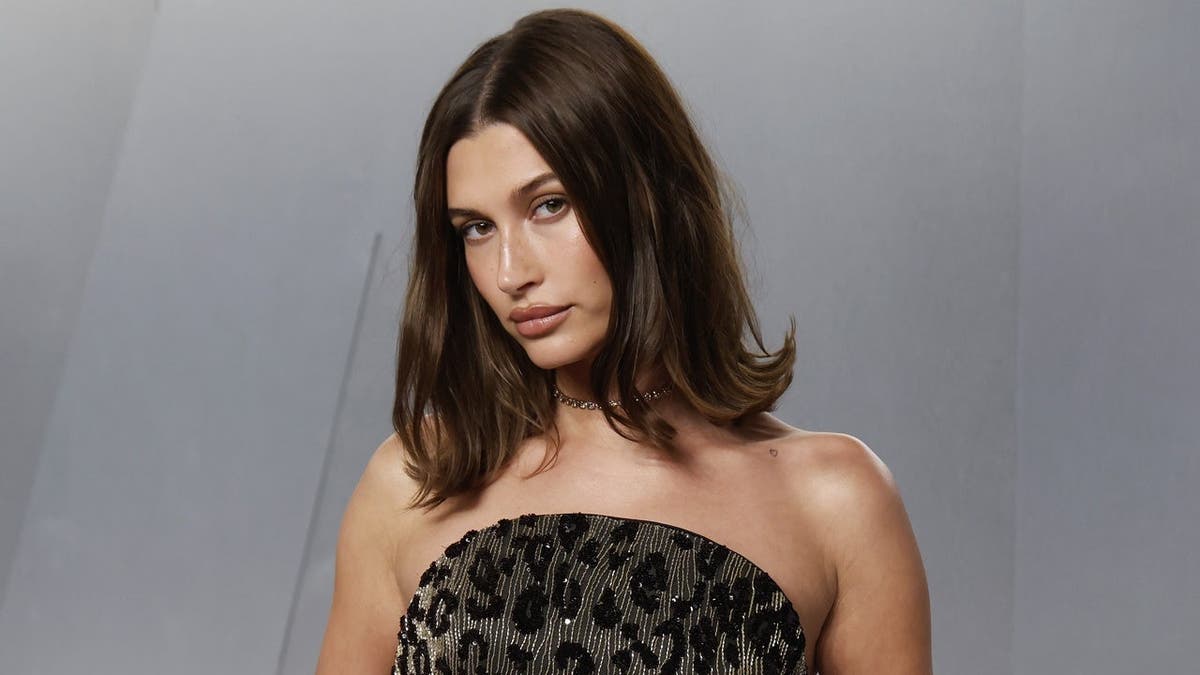 Hailey Bieber standing in a black dress at the Vanity Fair Oscar Party in Los Angeles