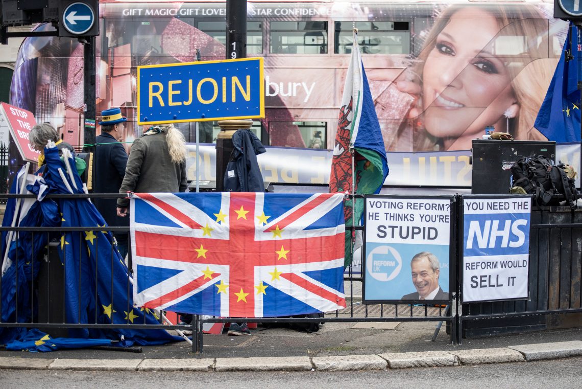 Signs and a hybrid UK-EU flag on a fence at the Parliament Square in London during a 2025 protest by British pro-EU activists urging the country to rejoin the European Union.