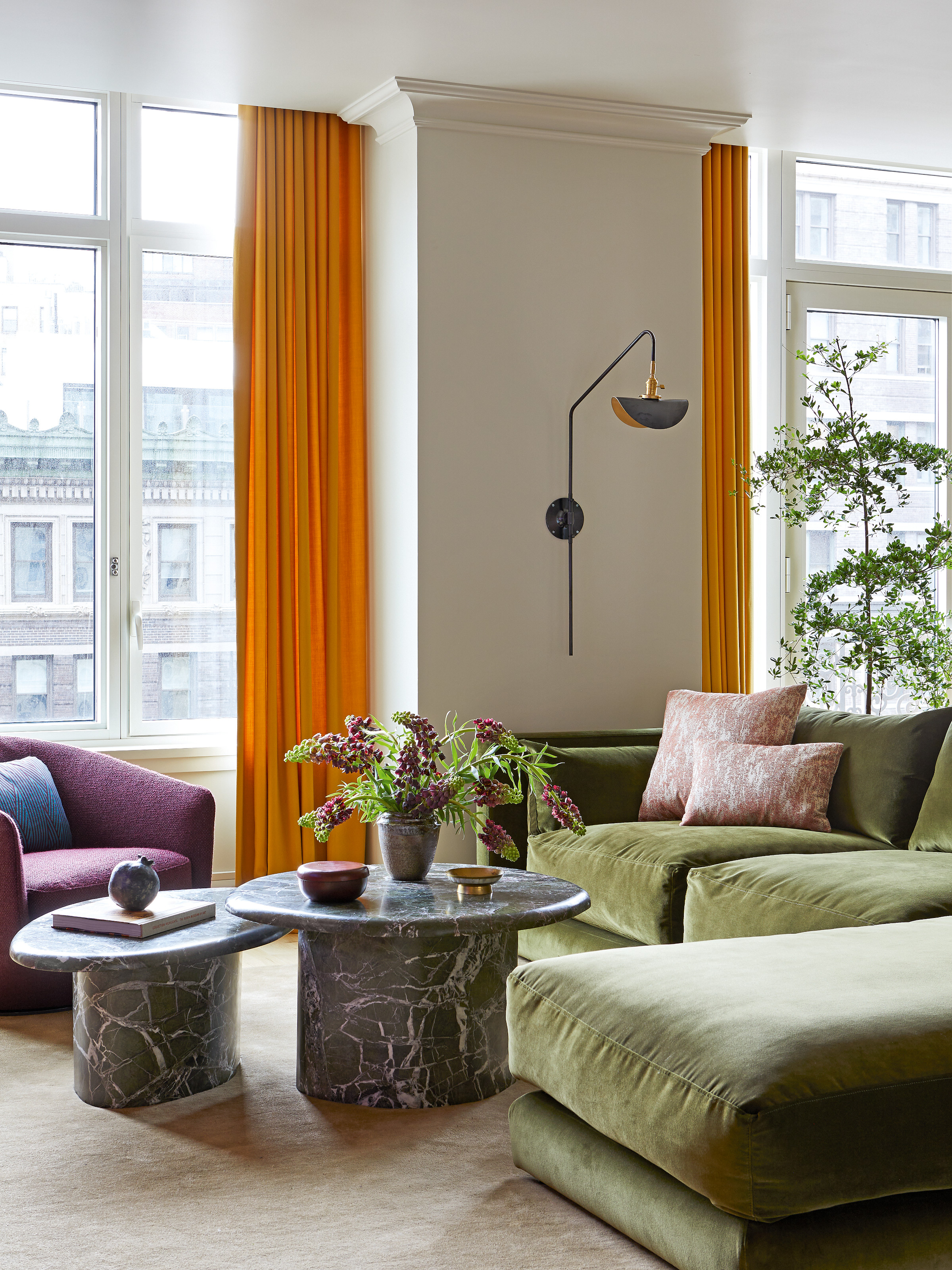 Living room with olive green chaise longue sofa, grey marble coffee tables, purple armchair and orange curtains