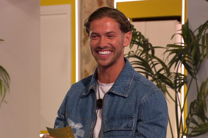Love Island S13 Kavan from Love Island smiling, wearing a denim jacket and white t-shirt.