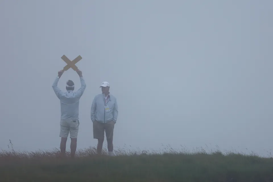 Marshals look on through the fog during the first round of the 126th U.S. OPEN