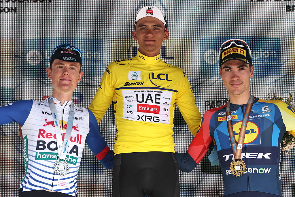 (From L) Overall second-placed Red Bull - Bora - Hansgrohe's Australian rider Luke Tuckwell, overall winning UAE Team Emirates XRG's Mexican rider Isaac Del Toro Romero wearing the overall leader's yellow jersey and third-placed Lidl-Trek's Spanish rider Juan Ayuso celebrate on the podium after the 8th and final stage of the Tour Auvergne-Rhone-Alpes cycling race (formerly known as the Criterium du Dauphine), 120,1km between Beaufort and Plateau de Solaison, in the French Alps on June 14, 2026. (Photo by Anne-Christine POUJOULAT / AFP)