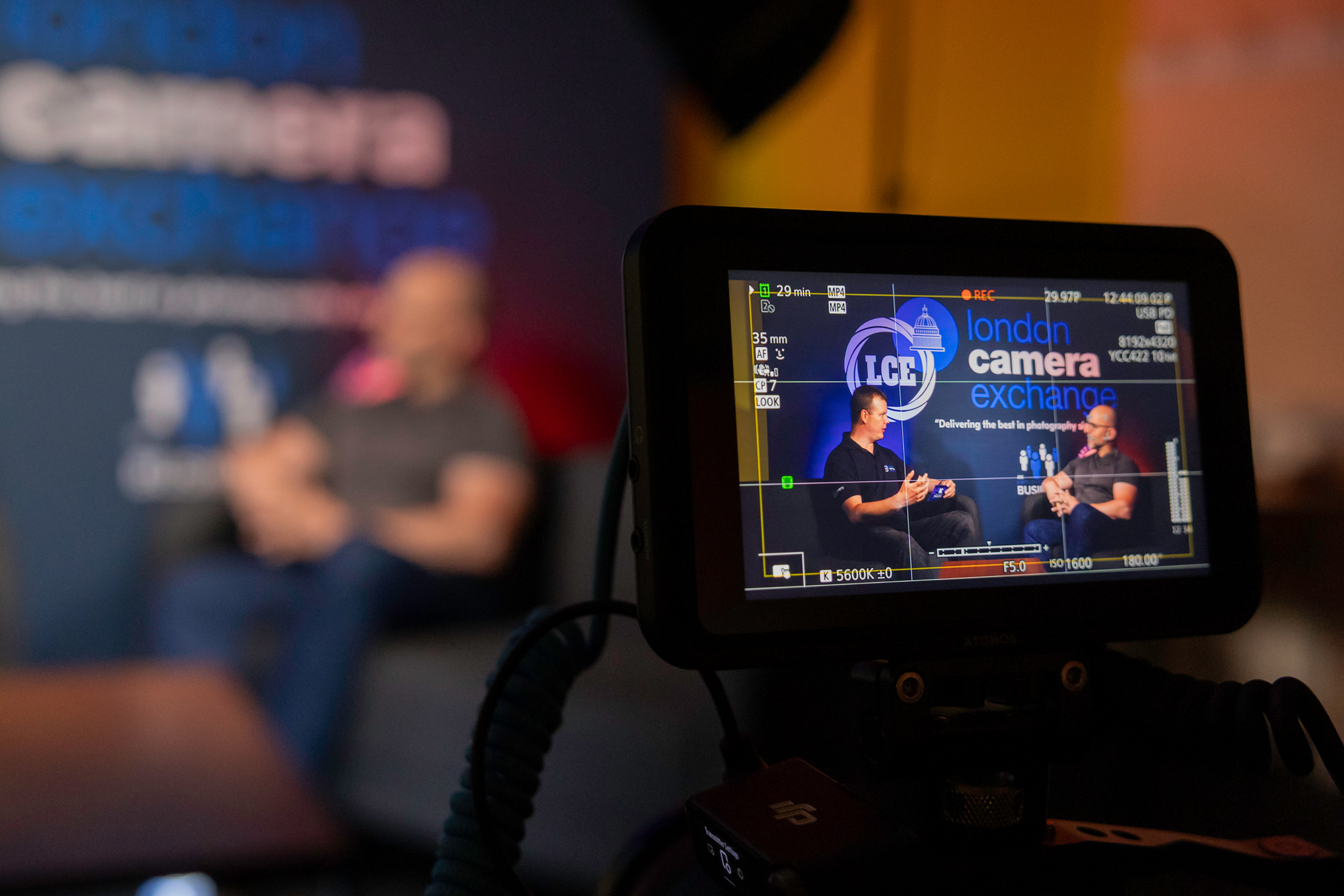 Camera screen showing two people being filmed during a London Camera Exchange interview or discussion event