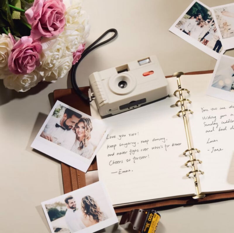 A table with a bouquet of roses, a vintage camera, instant photos of a couple, and an open guestbook featuring handwritten well-wishes for newlyweds.