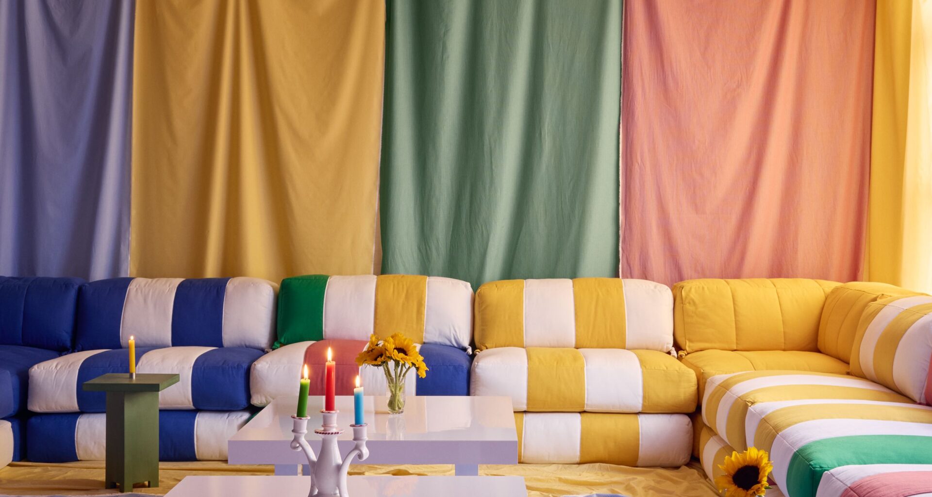 a room draped in colorful fabric with multicolor striped sofas and fabric on the floor