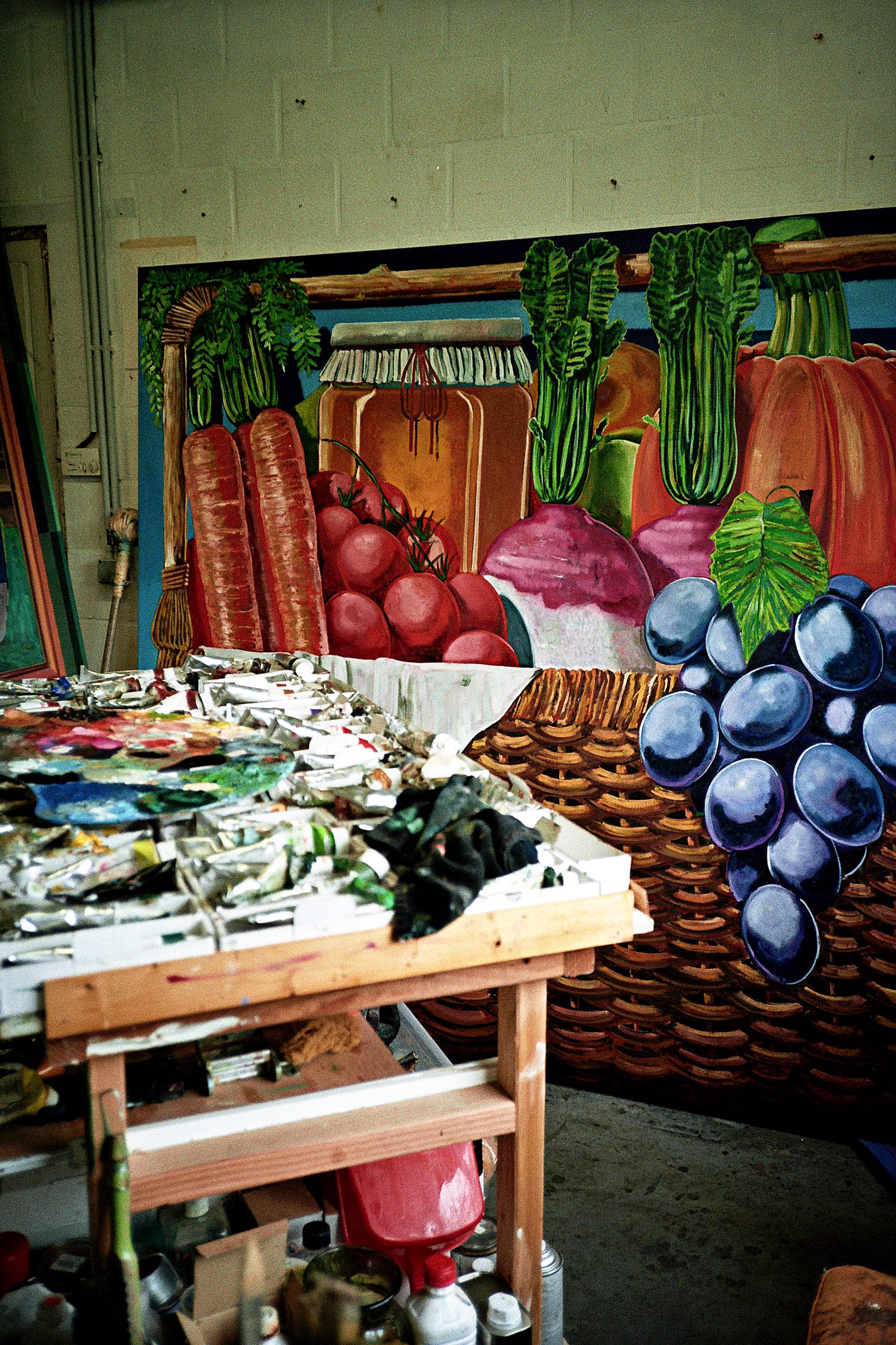 a photo of a large produce painting by Kristof Santy resting on the wall and a work table