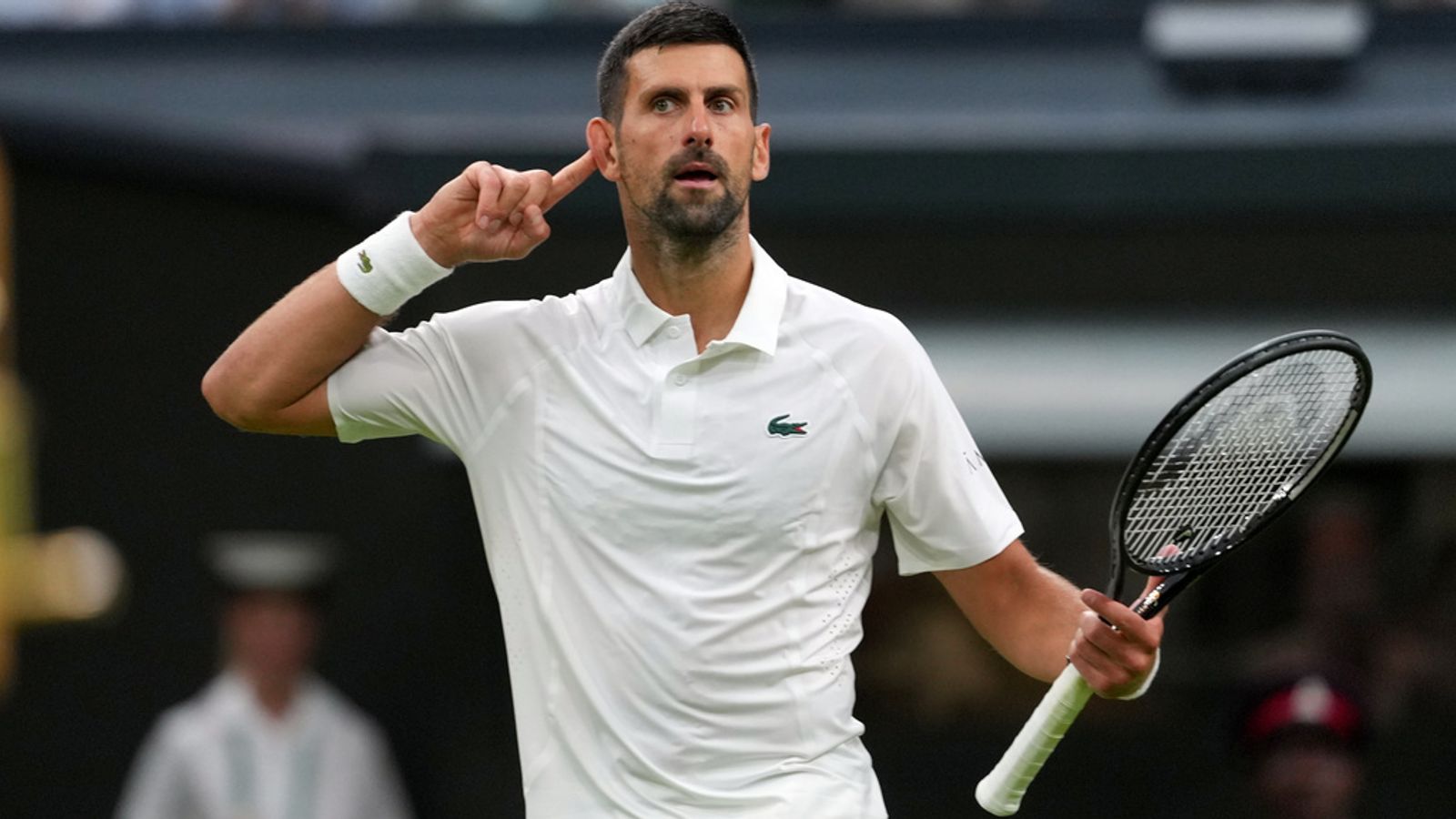 Novak Djokovic puts his finger to his ear after making a crucial break during his first-round battle at Wimbledon