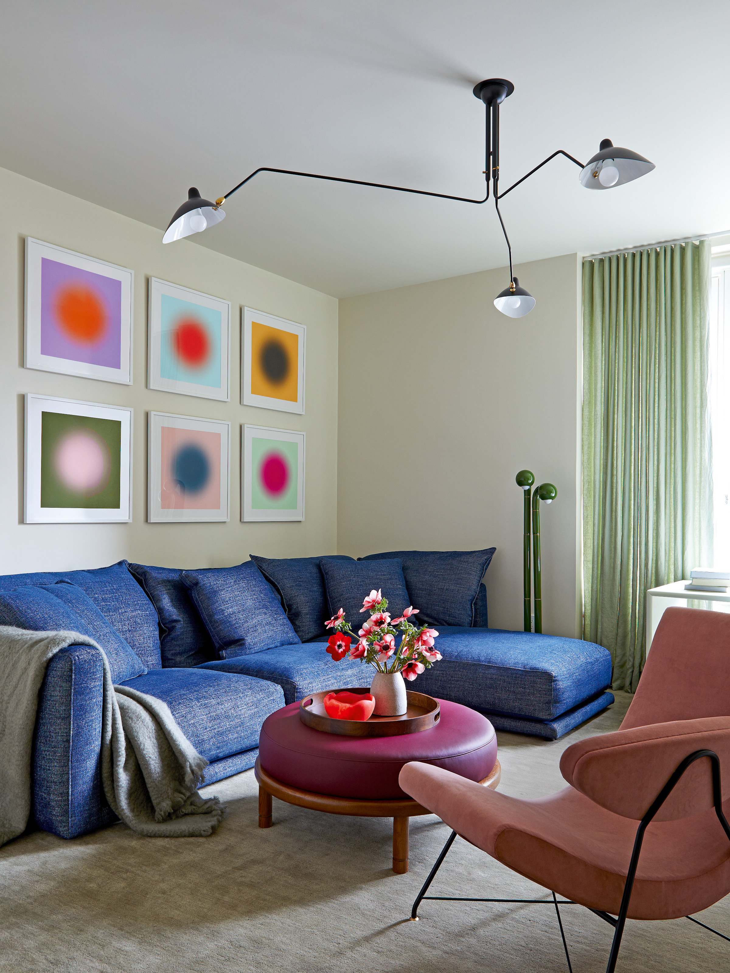 Family room with blue corner sofa, abstract artwork, pink armchair and purple ottoman