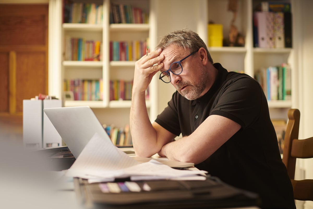 A stressed retiree is staring at a laptop screen.