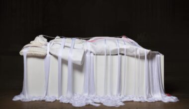 a mixed media white rope sculpture of a female figure laying down, referencing noble sculptures on top of sarcophagi, with draping ropes pooling at the floor