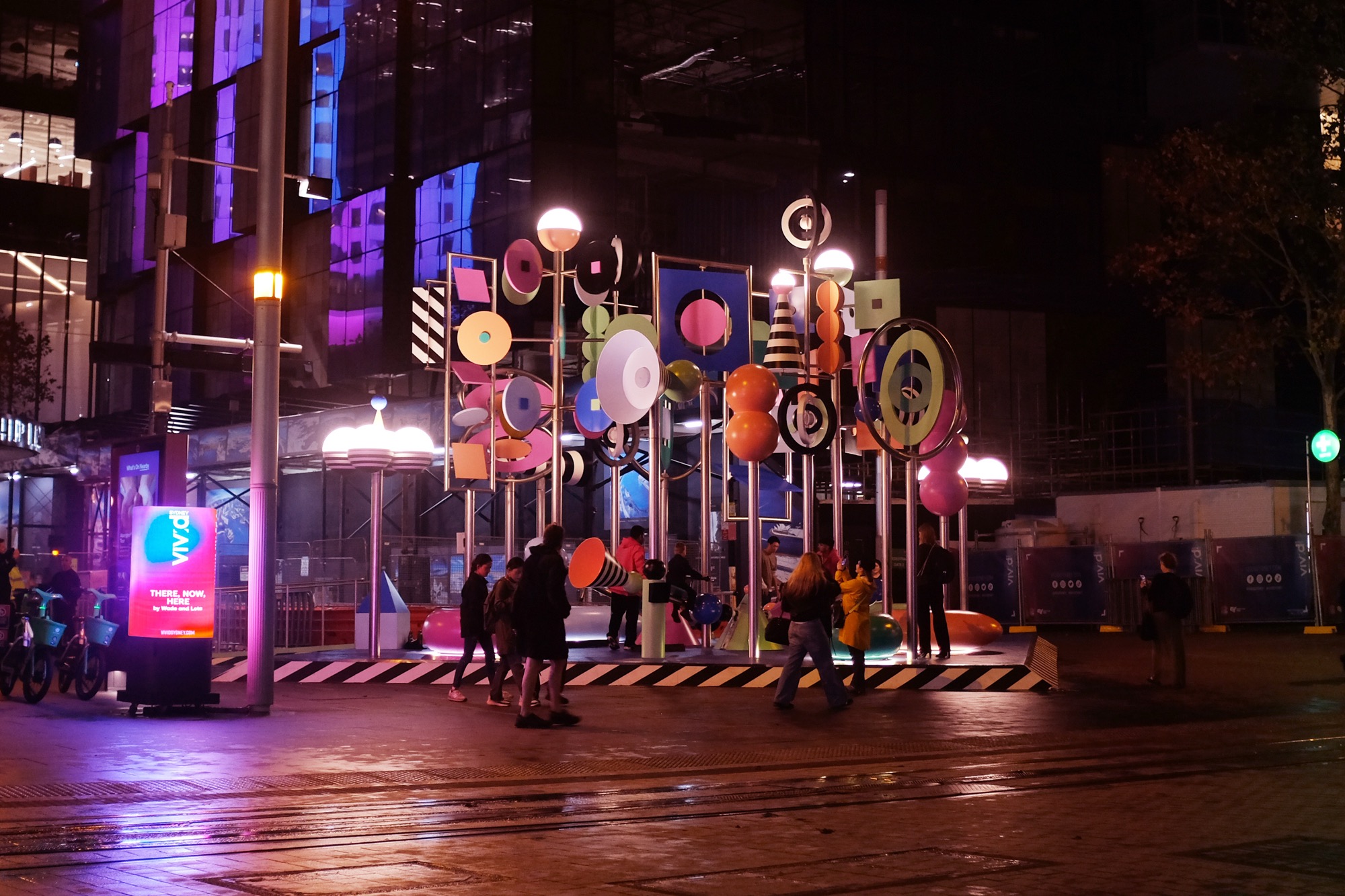 a photo of a colorful outdoor sculpture with twirling shapes by Wade and Leta at night