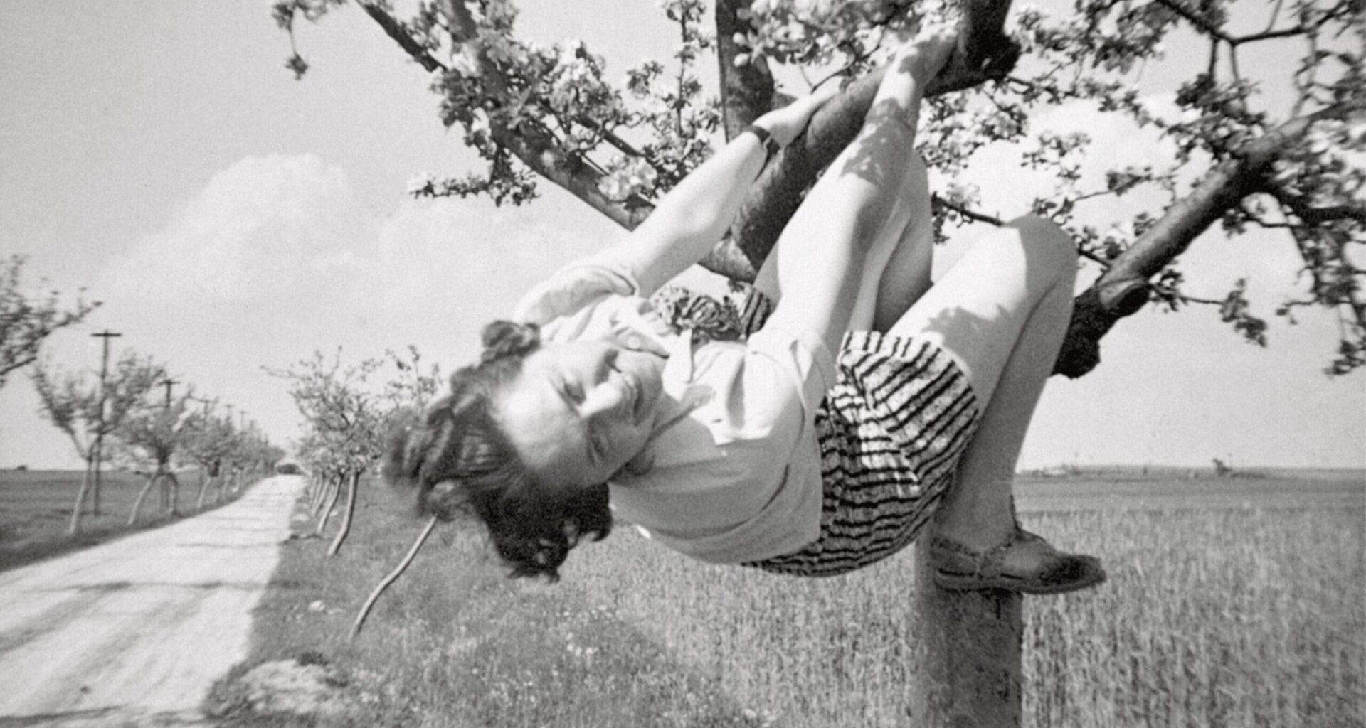 a black-and-white snapshot of a woman in a tree